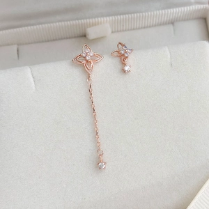 Detail of rose gold earrings with zircon flowers and asymmetric long tassel chain