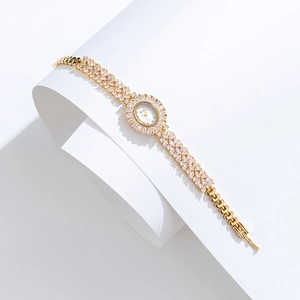 Close-up of golden oval watch with crystals and Minerva logo on a clean white background