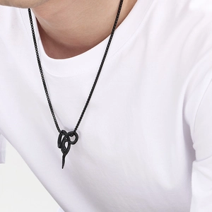 Close-up of a black punk style snake pendant necklace worn over a plain white T-shirt