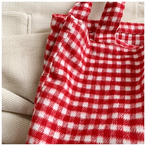Detailed close-up showing stitching on red and white checkered canvas shoulder bag strap
