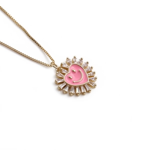 Collier doré avec pendentif smiley cœur rose et bordure en zircon sur fond blanc
