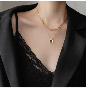 Close-up of double-layer gold necklace featuring a black rectangle pendant on a model