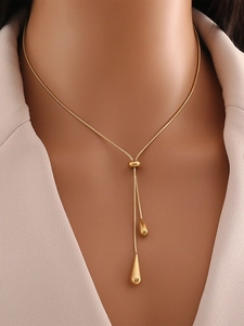 Detailed close-up of golden waterdrop tassel necklace with polished snake chain design