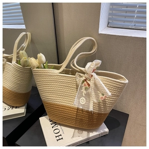 Close-up of woven tote bag featuring floral embroidery and lace bow details