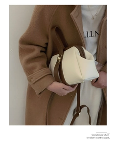 Close-up of retro color-block handbag with gold clasp on camel coat model