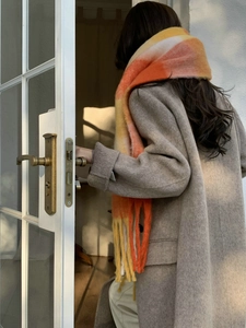 Close-up of soft orange and yellow gradient rainbow checkered scarf with tassel details
