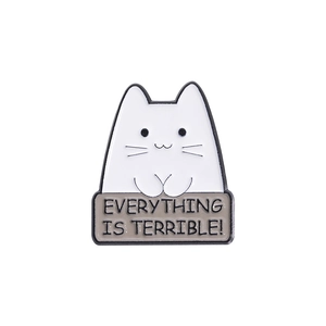 Detail of cartoon white cat enamel pin holding a sign saying EVERYTHING IS TERRIBLE