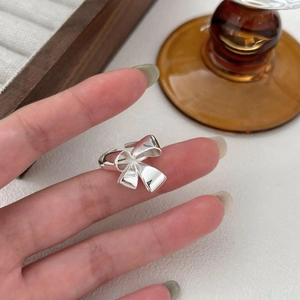Detailed view of polished S925 sterling silver bow knot ring on hand in a lifestyle setting