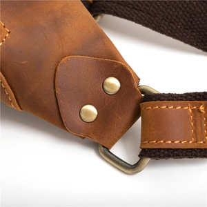Détail macro de la bandoulière en cuir marron avec boucle en D en bronze et rivets