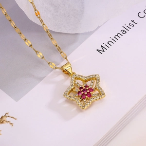 Elegant gold plated star pendant necklace with red and white zircons on a minimal book