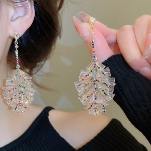 Macro detail of leaf-shaped earrings with colorful crystals and gold metal finish