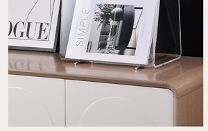 Close-up of clear acrylic magazine rack with silver metal base on a wooden desk