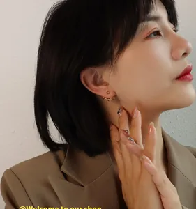 Close-up of elegant gold beaded earrings in a minimalist arc design on a model