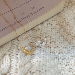 Detailed view of crescent moon pendant with pearl on gold and silver necklaces