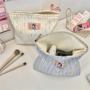 Détail de trousses de maquillage en tweed rayé avec écusson de vache rose de dessin animé