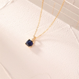 Macro shot of elegant gold necklace featuring a square deep blue zircon pendant with diamond