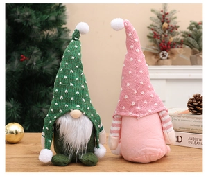 Primo piano di gnomi natalizi in maglia verde e rosa con barbe di peluche su legno