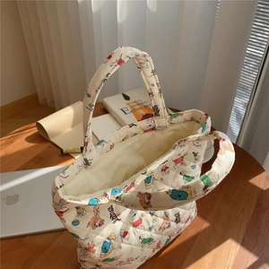 Detailed view of beige quilted handbag with colorful cartoon dog patterns on a wooden desk