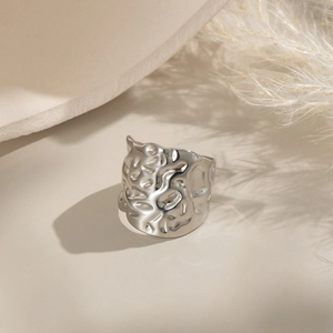 Close-up of a silver wide ring with geometric pleated texture and glossy metallic finish