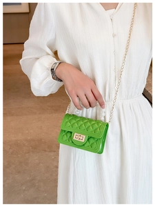 Macro shot of green jelly bag with pearl handle and golden chain on a white dress