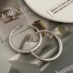 Minimalist silver hoop earrings for women presented on an open art magazine with soft light