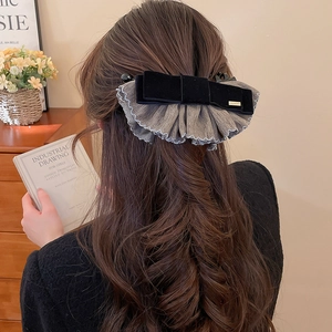 Détail d'une grande pince à cheveux en velours noir et tulle gris au style rétro chic