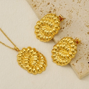 Detailed view of gold stainless steel knot necklace and earrings set on textured stone
