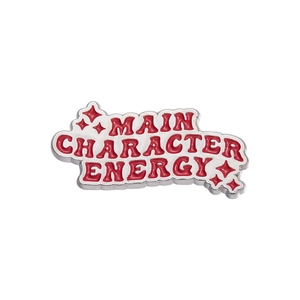 Rode emaille speld met Main Character Energy slogan en zilveren rand op witte achtergrond
