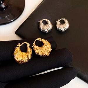 Detail of gold and silver croissant dome hoop earrings with elegant textured finish