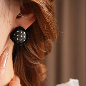 Close-up of retro black polka dot fabric square earrings worn on a female model