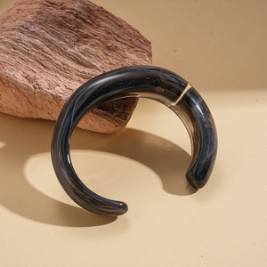 Macro detail of black marble texture resin cuff bracelet on natural stone background