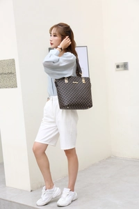 Detail of dark brown tote bag with geometric print and gold-tone hardware on a model