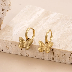 Elegant gold butterfly hoop earrings made of titanium steel displayed on a natural stone