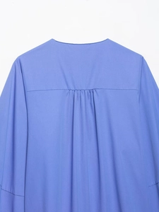 Détails du dos d'une chemise en popeline bleue avec plis fins et manches ballons