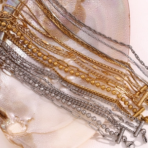 Detail of diverse layered gold and silver chain bracelets on a textured shell