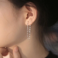 Close-up of silver long tassel chain earrings showing elegant drape on female model