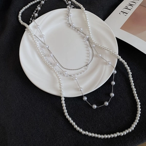 Detail of elegant French vintage multi-layer pearl necklace with silver chain on white plate
