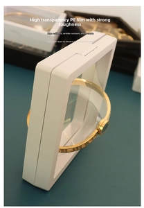Macro shot of white PE film suspension box holding a gold roman numeral bracelet