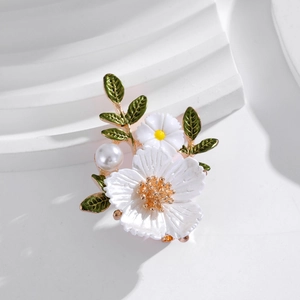 Broche marguerite élégante avec pétales en émail blanc, feuilles vertes et une perle
