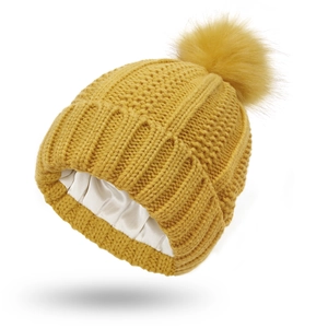 Detail of ginger knit beanie with silk satin lining and faux fur pom pom decoration