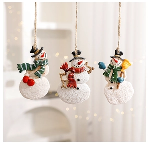 Three assorted resin Christmas snowman ornaments hanging with warm bokeh background
