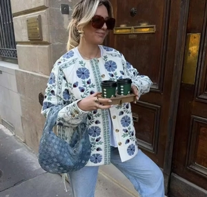 Détail d'une veste matelassée en coton avec broderie florale bleue et boutons dorés