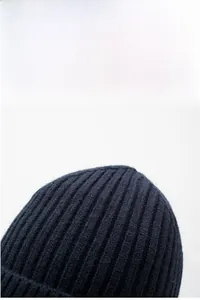 Detailed close-up of navy blue knit beanie showing soft ribbed texture and warm yarn fabric
