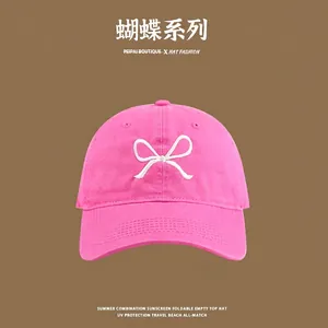 Close-up of bright pink baseball cap with detailed white bow embroidery and sun protection