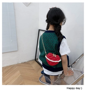 Girl wearing a red heart-shaped quilted bag with pearl handle and metal chain strap