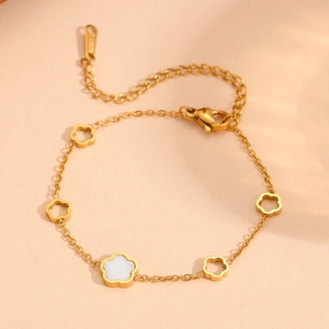 Detail of gold floral bracelet featuring hollow five-leaf flowers and a white shell inlay