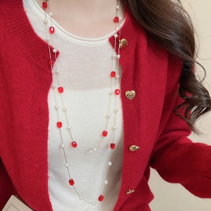 Detail of elegant double-layer necklace with red faceted beads and white pearls on gold chain