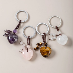 Close-up of four assorted natural crystal heart keychains with hand-woven cord straps