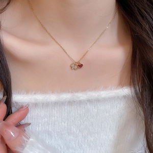 Gros plan du collier doré avec pendentif ours en zircon et cœur rouge sur modèle