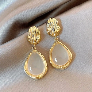 Vintage irregular gold drop earrings with white cat eye stones on champagne silk